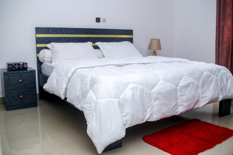 Chambre principale king-size avec tête de lit navy et or — appartement meublé Yaoundé